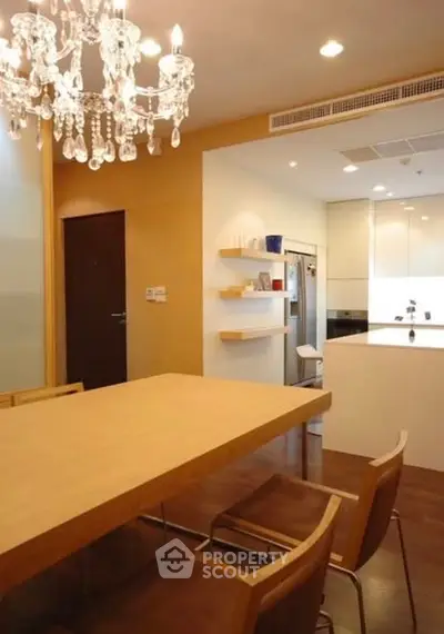Elegant dining area with chandelier and modern kitchen in open layout