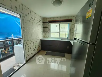 Modern kitchen with sleek design and stainless steel fridge, featuring open layout and ample natural light.