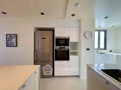 Modern kitchen with sleek appliances and minimalist design, featuring built-in oven and spacious fridge.