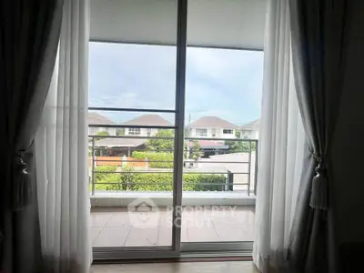 Spacious balcony with serene neighborhood view through sliding glass doors.