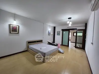 Spacious bedroom with modern decor and ample natural light, featuring minimalist design and cozy ambiance.