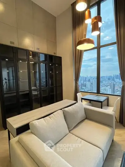 Modern living room with high ceilings and city view, featuring elegant furniture and large windows.