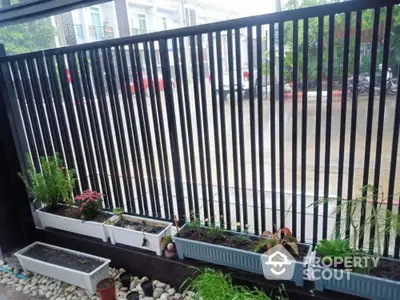 Charming garden view with modern fence and planter boxes in a residential area.