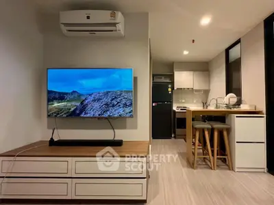 Modern living room with wall-mounted TV and compact kitchen in open layout apartment