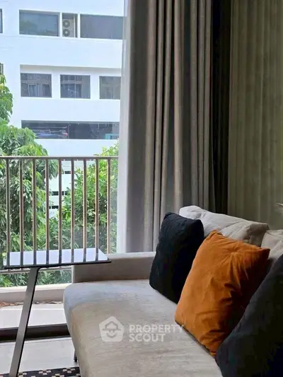 Modern living room with cozy sofa and large window offering lush green view.