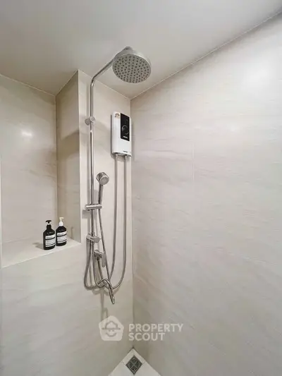 Modern bathroom shower with sleek fixtures and built-in shelf for toiletries.