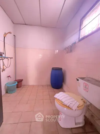 Spacious bathroom with tiled floor, shower, and natural light from window.