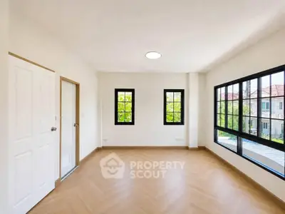 Spacious empty room with large windows and wooden flooring