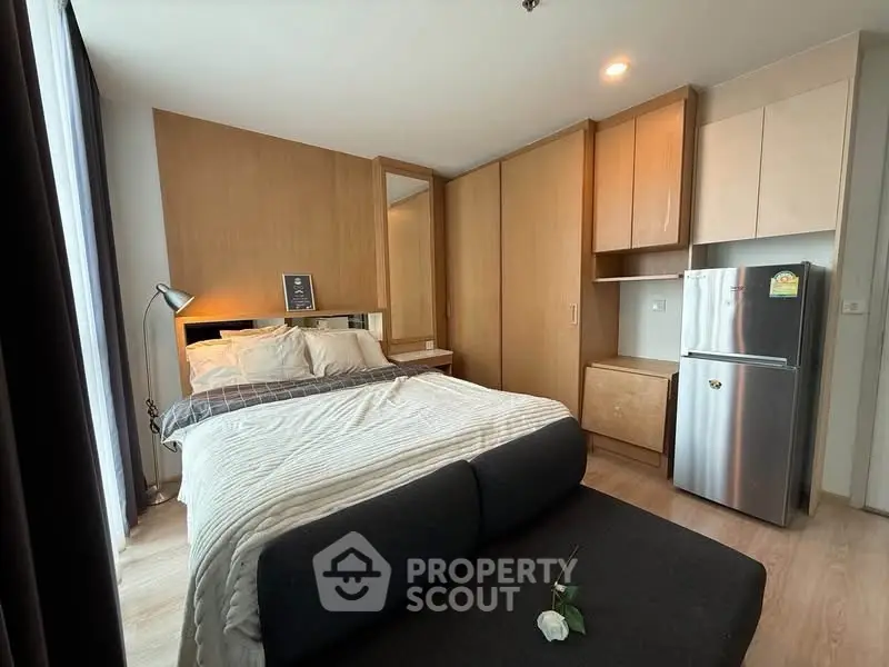 Modern bedroom with cozy bed, stylish lighting, and compact kitchenette in a chic apartment.