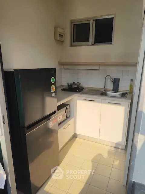 Compact kitchen with modern appliances and sleek cabinetry in a cozy apartment setting.