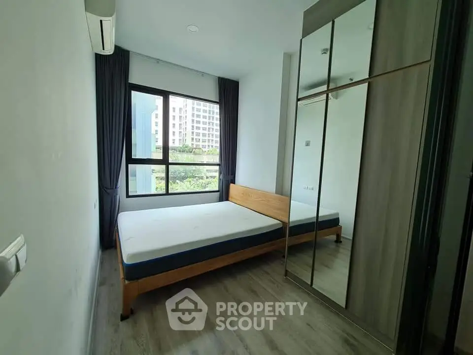 Modern bedroom with large window and mirrored wardrobe in a stylish apartment.