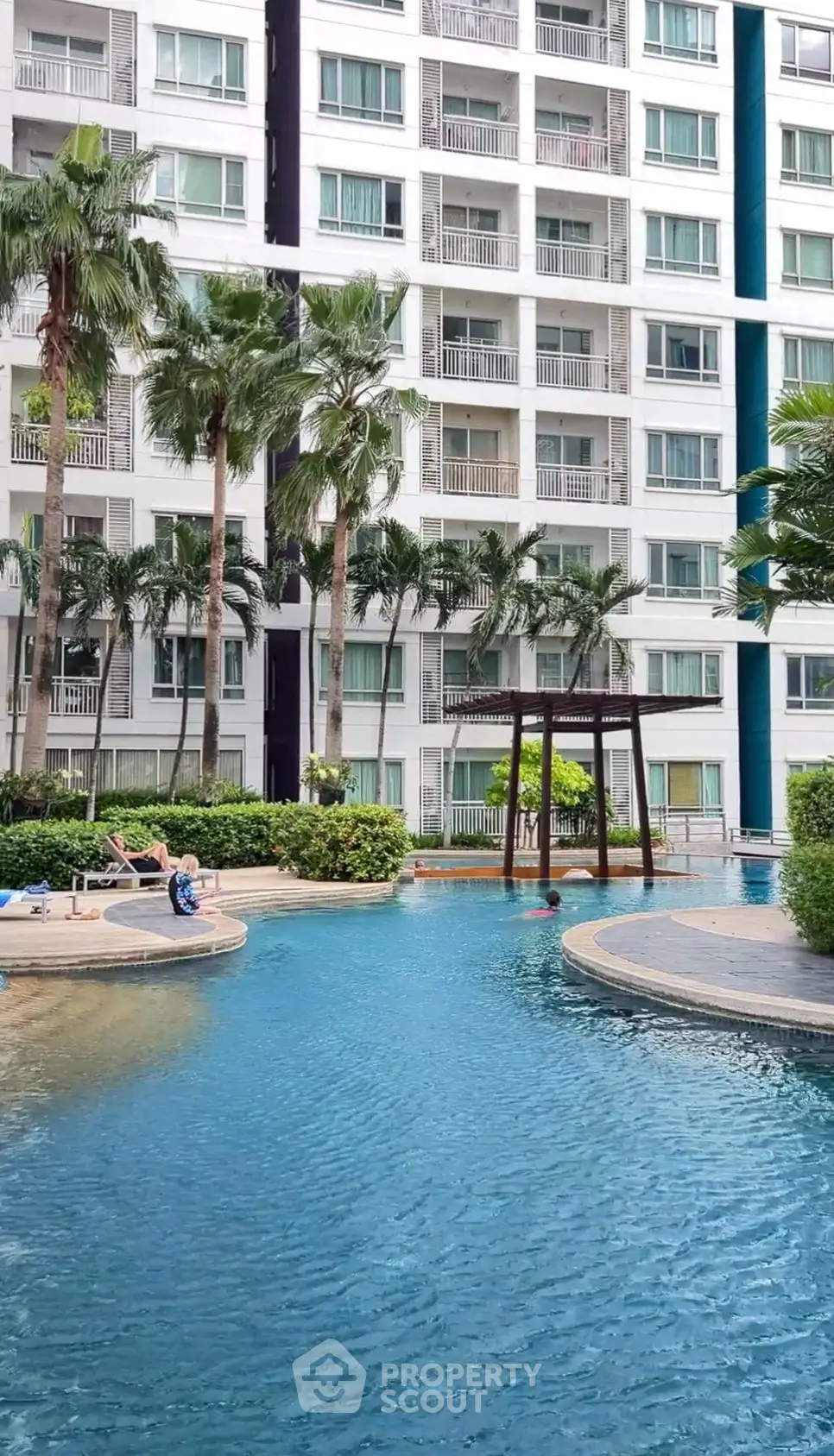 Luxurious apartment complex with stunning pool and lush palm trees, perfect for relaxation and leisure.