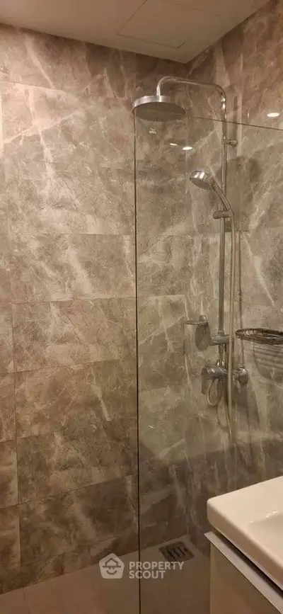 Modern bathroom with elegant marble tiles and sleek glass shower enclosure.