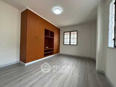Spacious bedroom with wooden built-in closet and large windows for natural light