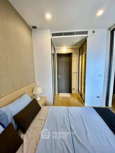 Modern bedroom with sleek design and ample natural light, featuring a cozy bed and stylish decor.
