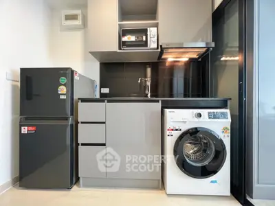 Modern compact kitchen with appliances including fridge, microwave, and washing machine.