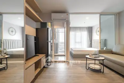 Modern open-plan apartment with stylish living area and bedroom, featuring sleek furniture and natural light.