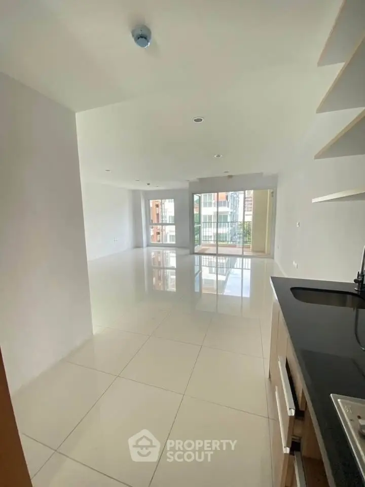 Spacious open-plan living area with modern kitchen and large windows in a contemporary apartment.