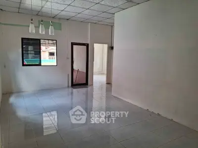 Spacious empty room with tiled flooring and modern lighting fixtures.