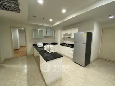 Modern kitchen with sleek countertops and stainless steel appliances in a spacious apartment.