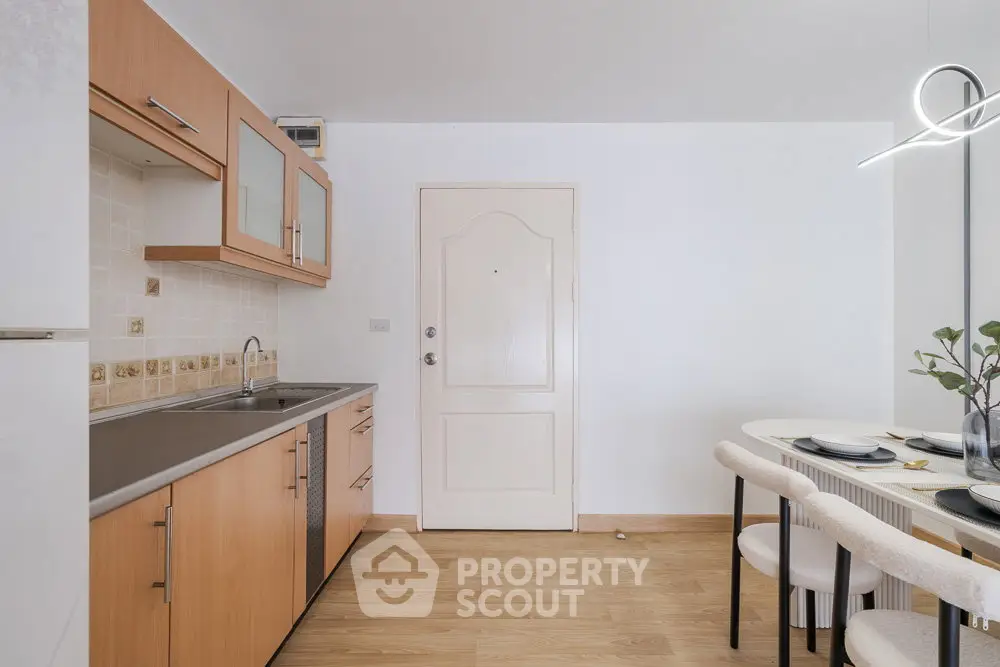 Modern kitchen with wooden cabinets and dining area in a cozy apartment.