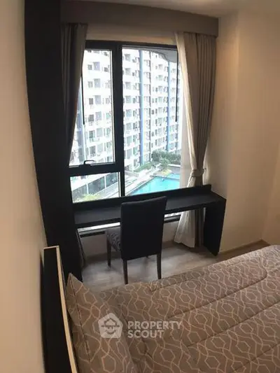 Cozy bedroom with a view of the pool and modern high-rise buildings.