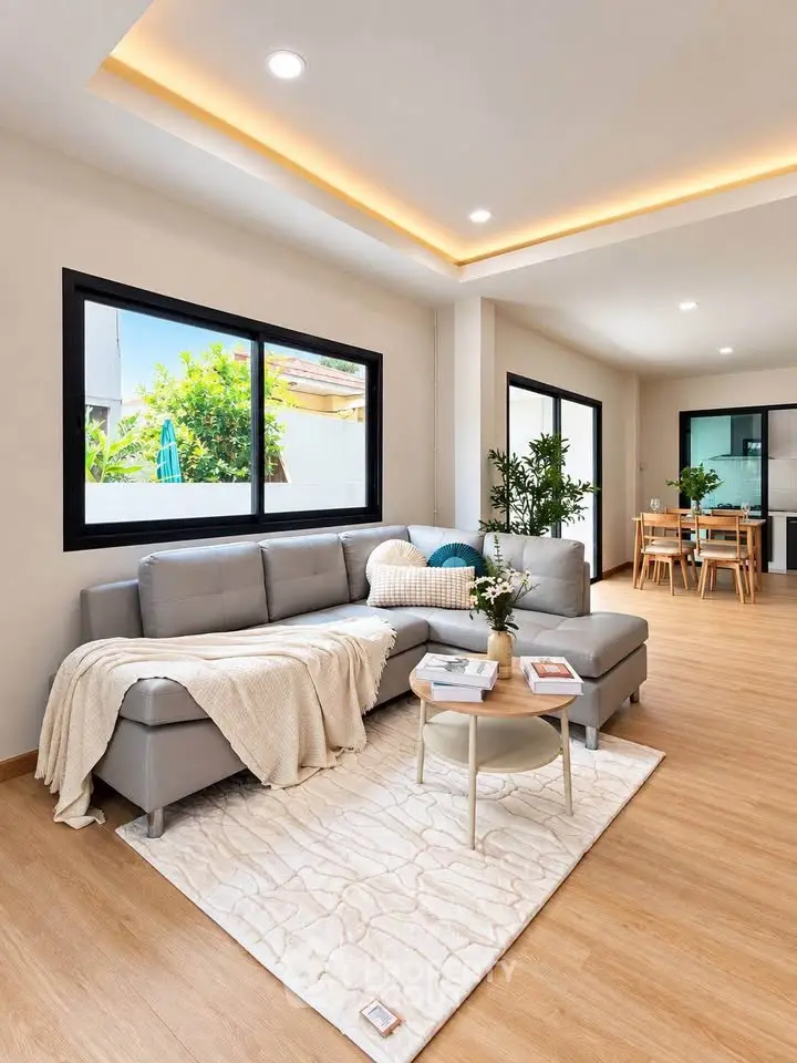 Modern living room with cozy sectional sofa and elegant decor, featuring large windows and open layout.
