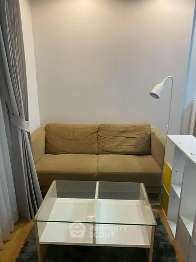 Cozy living room with a beige sofa and modern glass coffee table, perfect for relaxation.