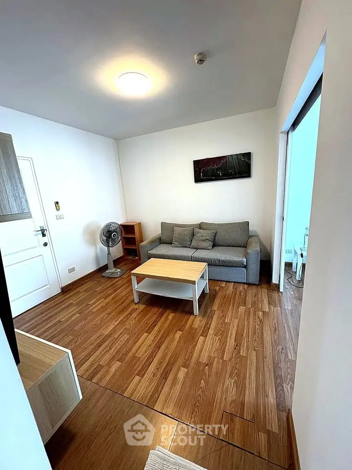 Modern living room with wooden flooring and cozy gray sofa in a stylish apartment.