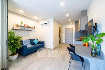 Modern living room with stylish decor and open kitchen layout, featuring a cozy blue sofa and sleek furniture.