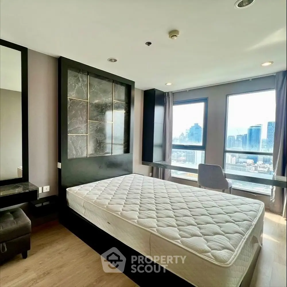 Modern bedroom with city view and stylish decor in high-rise apartment.