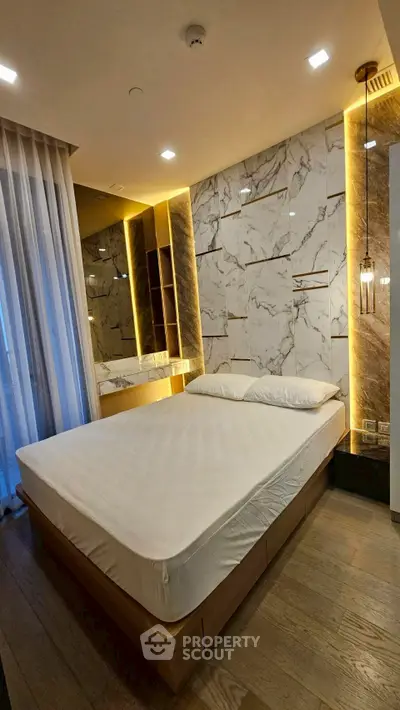 Luxurious bedroom with marble accent wall and modern lighting in upscale apartment.