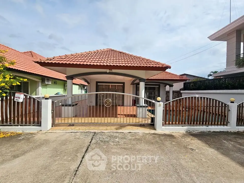 Charming single-story house with red-tiled roof and gated entrance in a serene neighborhood.