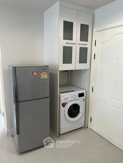 Modern apartment with sleek kitchen appliances including fridge and washing machine.