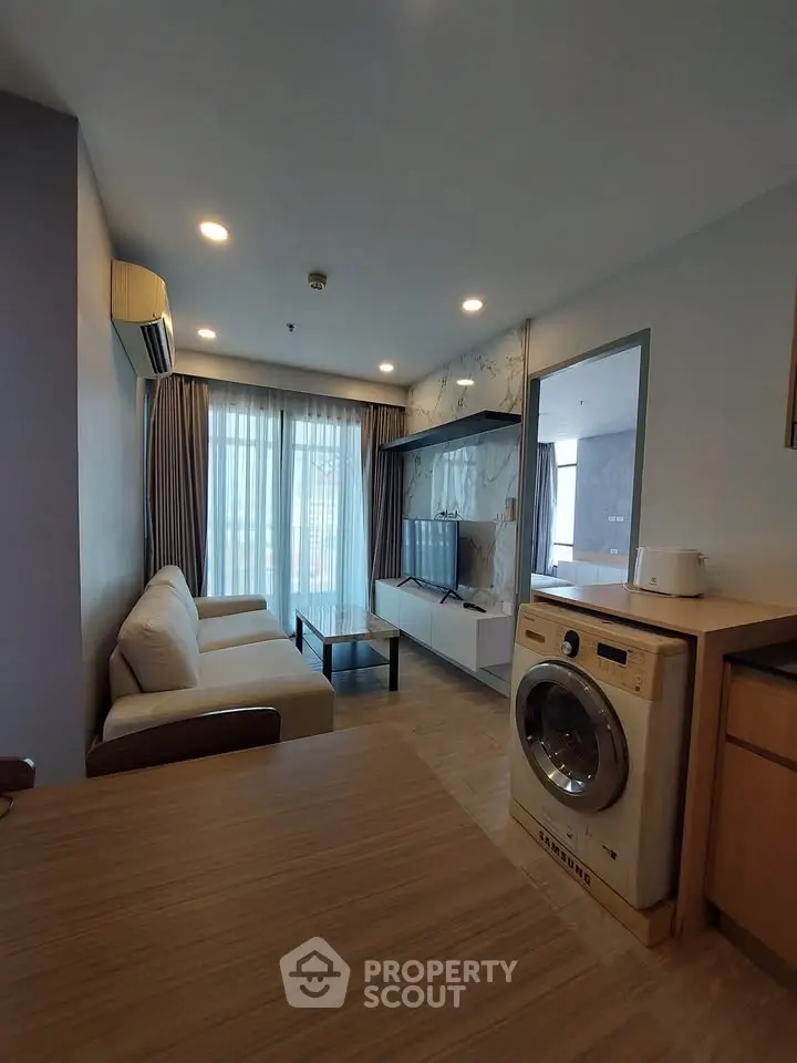 Modern living room with washing machine and cozy sofa in stylish apartment