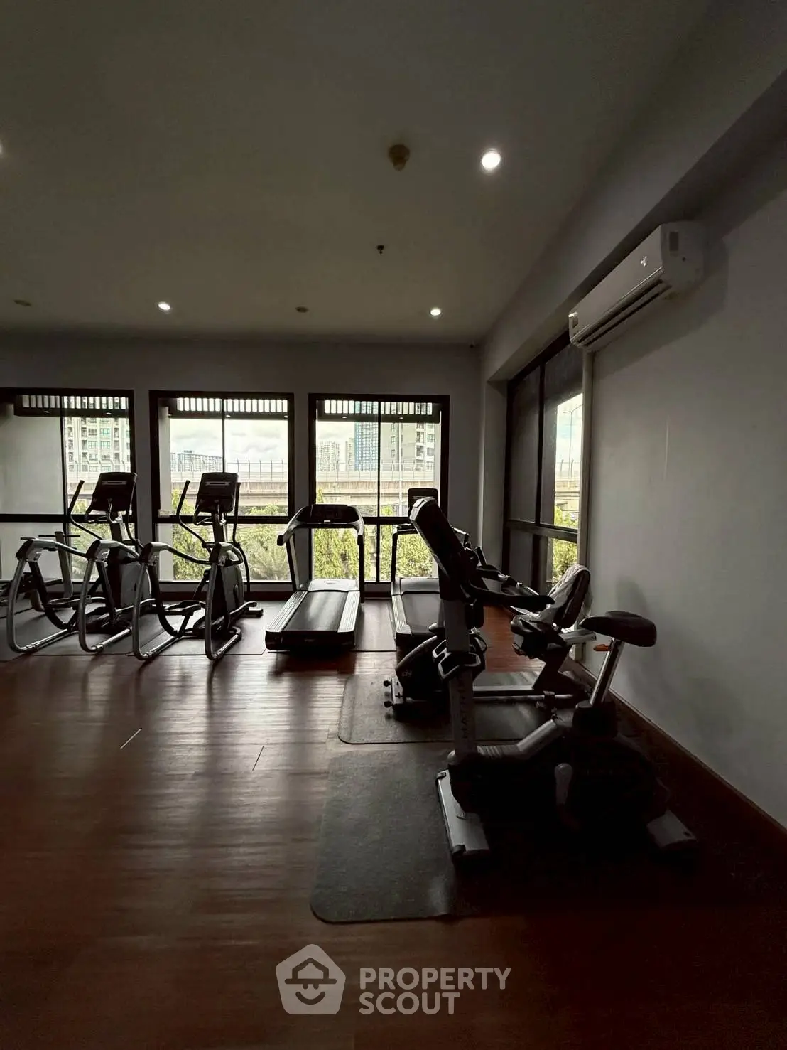 Modern gym with exercise equipment and large windows offering city views.