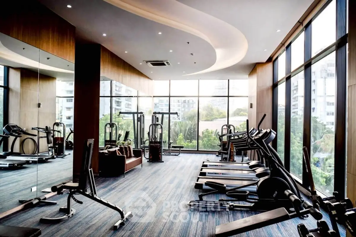 Luxurious gym with modern equipment and panoramic city views in upscale residential building.