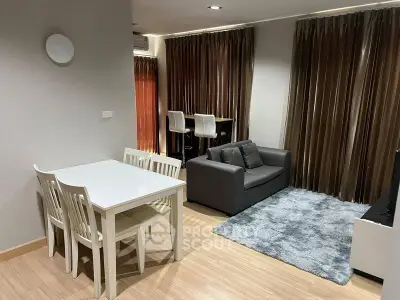 Modern living room with cozy seating and dining area, featuring elegant curtains and wooden flooring.