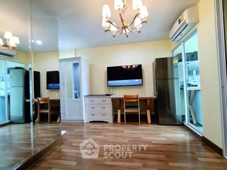 Charming living room with elegant chandelier and modern appliances in a cozy apartment.