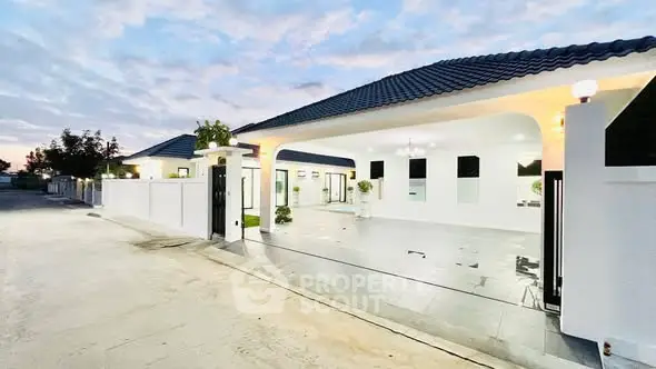 Modern white house with sleek design and spacious driveway at sunset.
