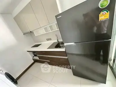 Modern kitchen with sleek cabinetry and stainless steel fridge in compact layout.
