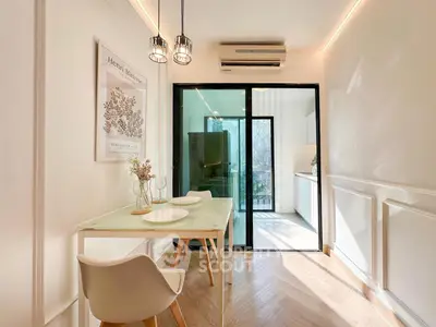 Modern dining area with glass table, stylish chairs, and sliding glass door leading to a bright kitchen.
