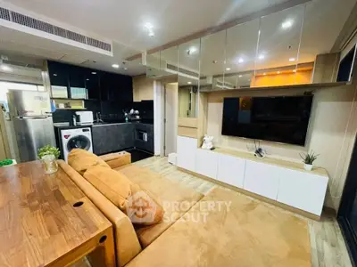 Modern living room with open kitchen, featuring sleek design and cozy seating area.