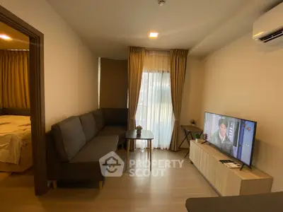 Modern living room with cozy sofa and TV, adjacent to a bedroom, featuring elegant curtains and wooden flooring.