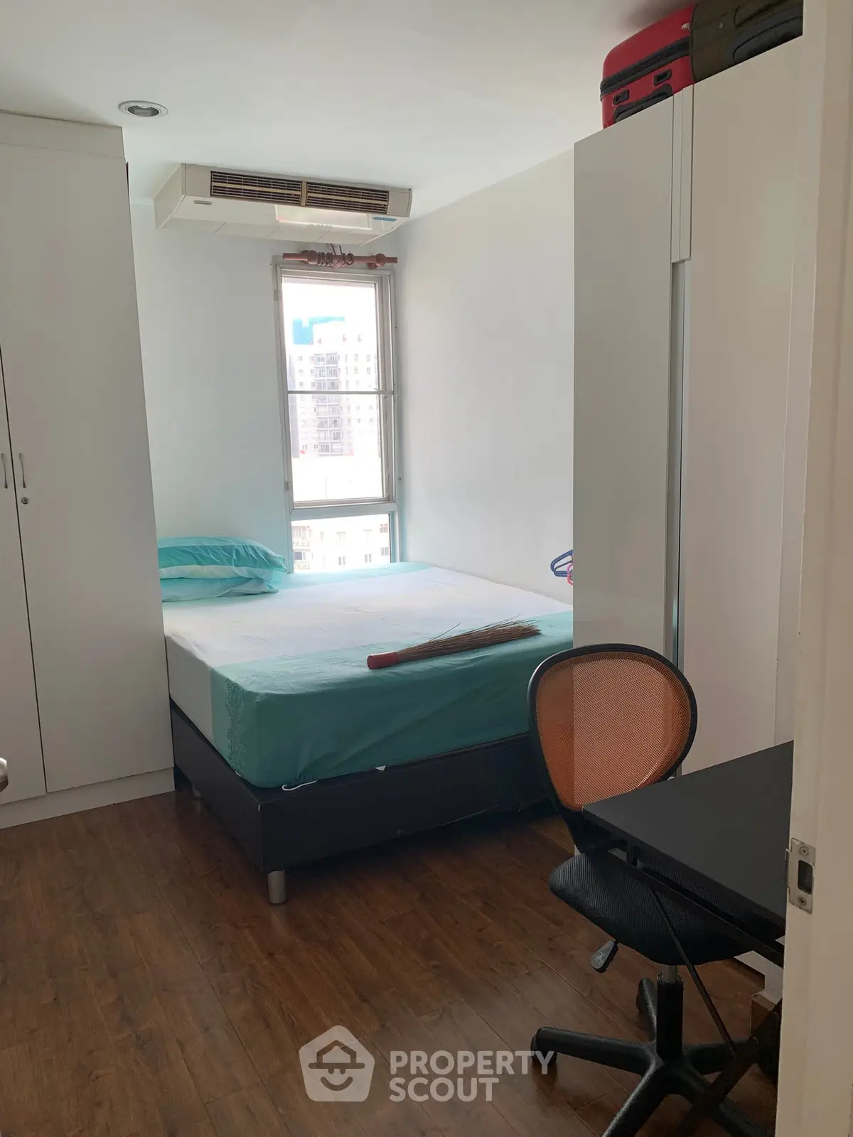 Cozy bedroom with modern furnishings and city view window, ideal for urban living.