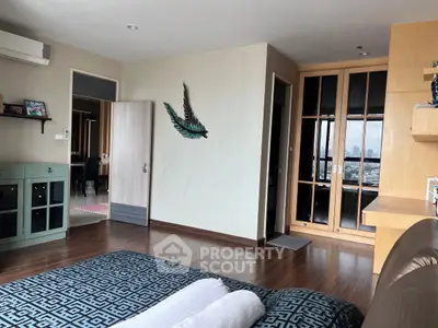 Spacious bedroom with wooden flooring and city view, featuring modern decor and ample natural light.
