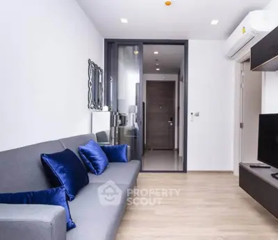 Modern living room with sleek design and blue accent pillows, featuring a comfortable gray sofa and wall-mounted TV.