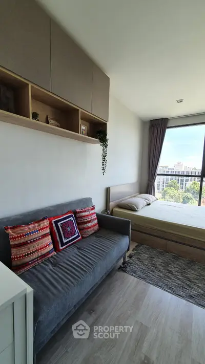 Modern bedroom with cozy sofa and large window offering city view