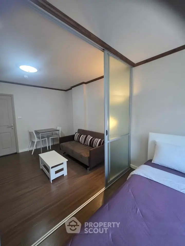 Modern studio apartment with sliding glass partition and cozy furnishings