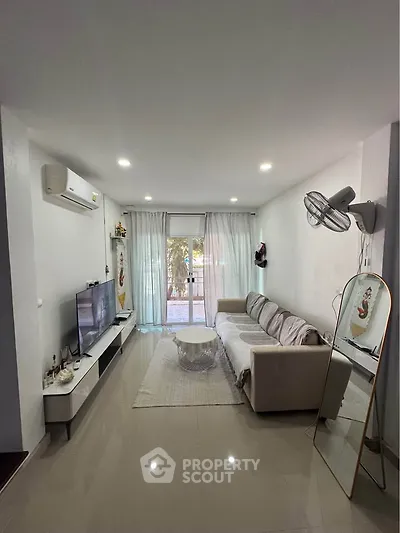 Modern living room with sleek furniture and natural light, featuring a cozy sofa and wall-mounted TV.